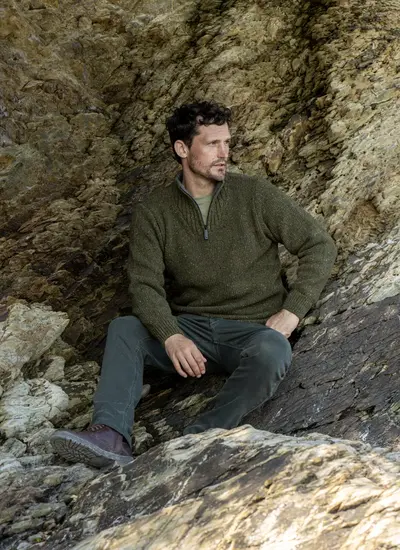 Man sitting on rocks wearing Glenstone Contrast 1/2 Zip Sweater in earthy tones, styled with outdoor hiking boots.